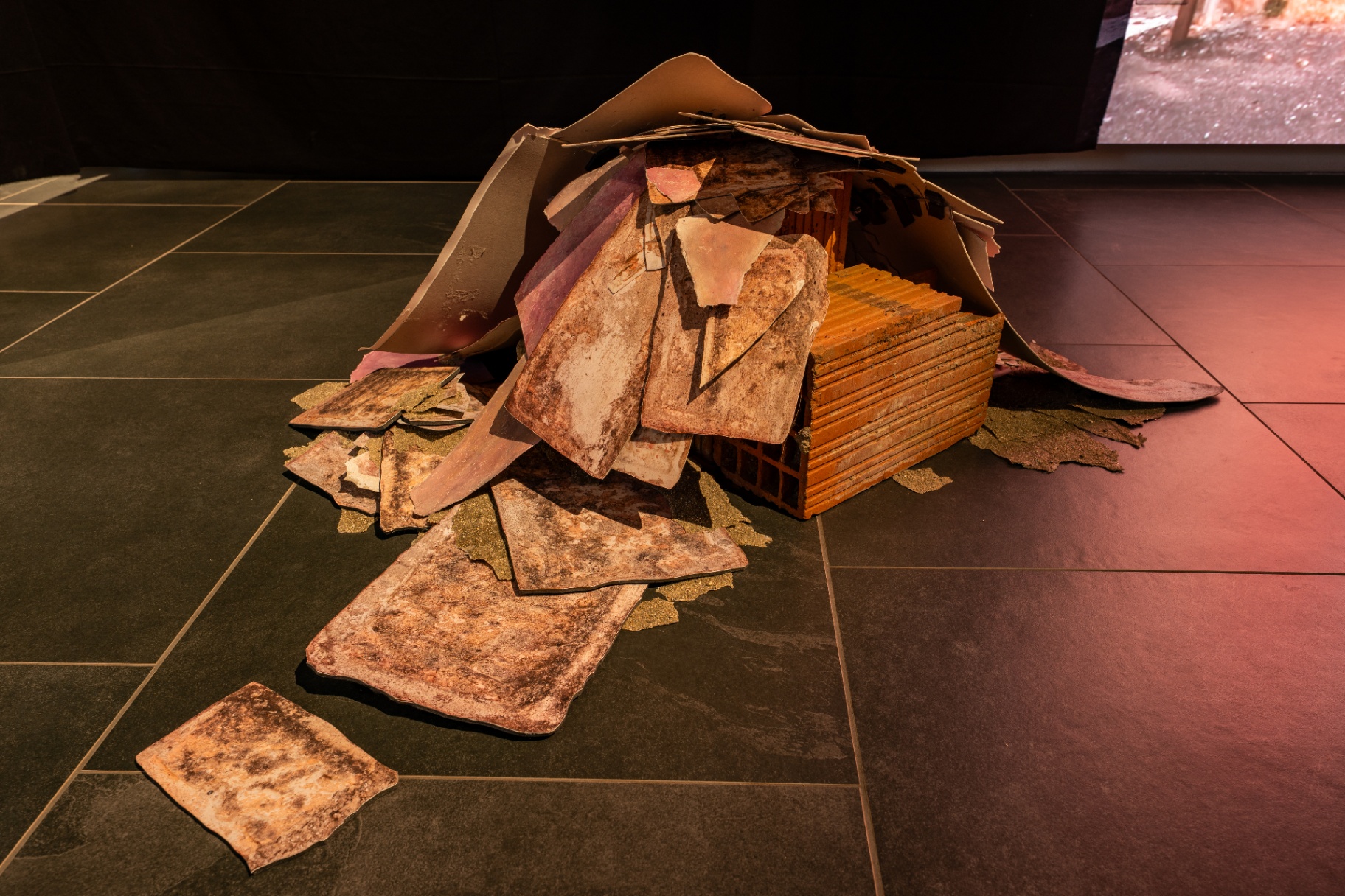 Campo luminoso — accumulo di mattoni e frammenti di terracotta su pavimento scuro